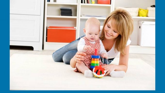 Baby playing with toys with happy mother